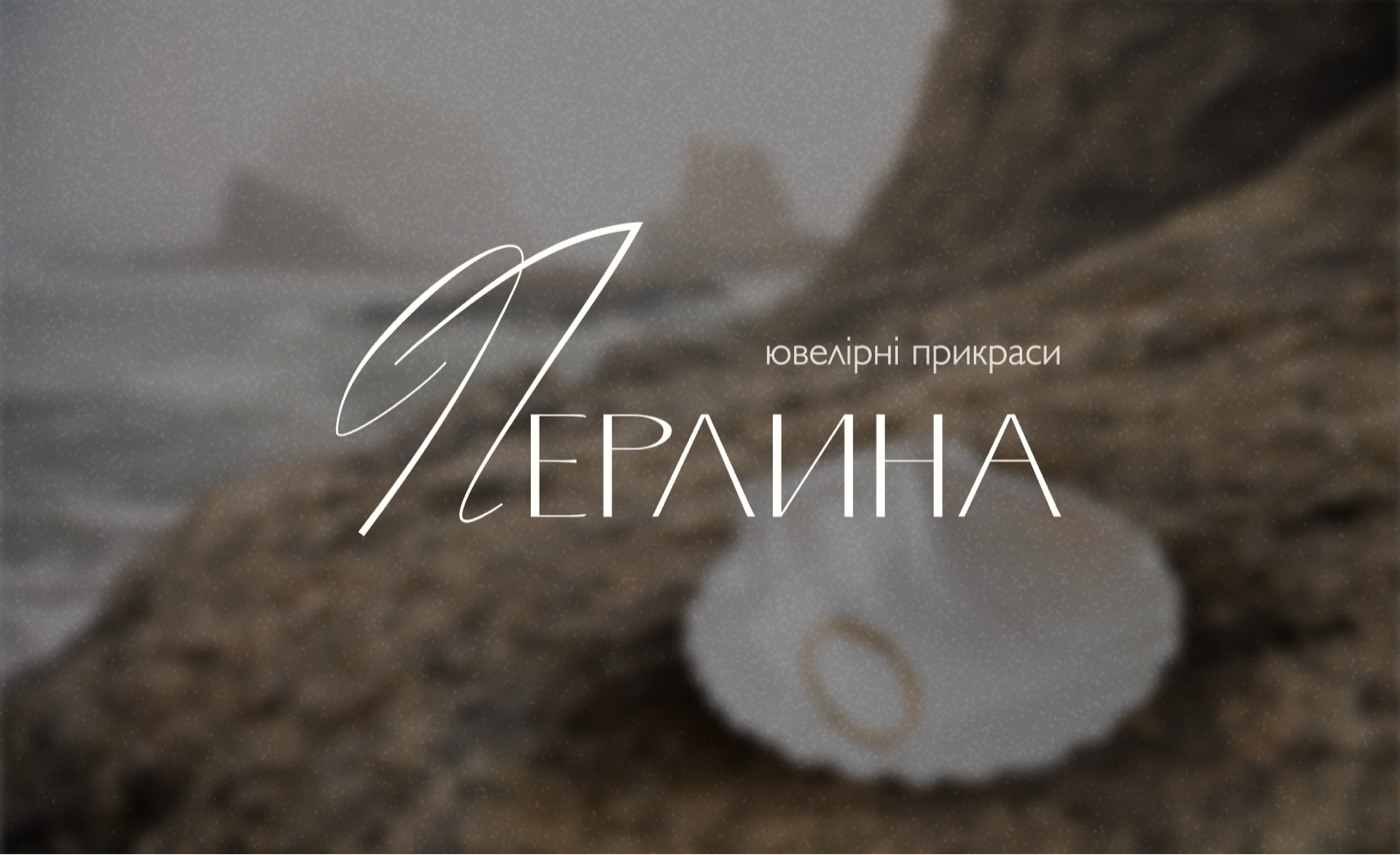 Perlyna logo on a pearl shell against coastal rocks